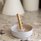 White ceramic dish with a wooden stick on a marble surface