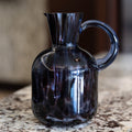 Glass pitcher with a handle on a marble surface