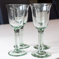 Two clear glass wine glasses on a white surface with a blurred background