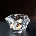 Clear mid-century modern glass candle holder  and paper wieght with a candle on a dark background