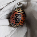 Decorative egg with tribal patterns on a light fabric background