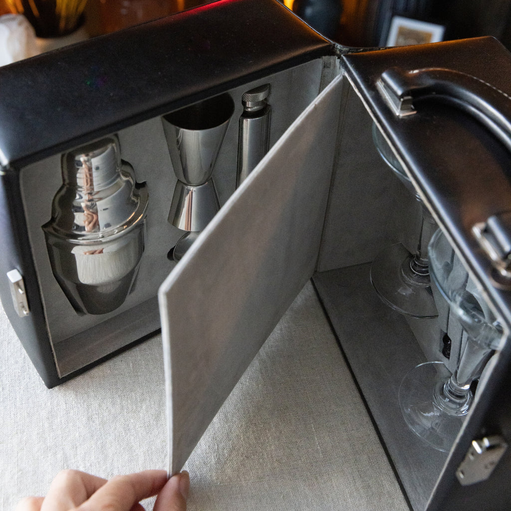 Cocktail shaker set in a black leather case on a light gray surface.