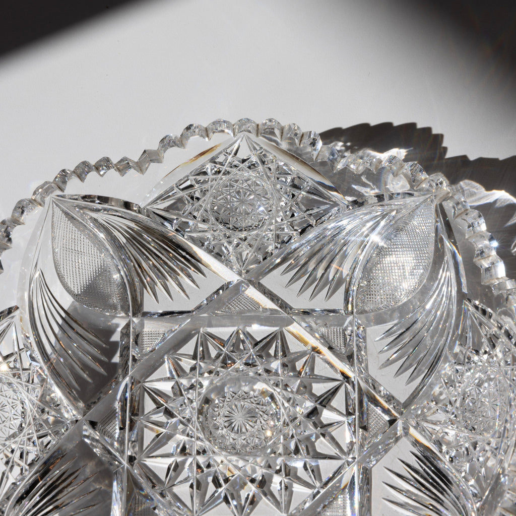 Close-up of a crystal bowl with intricate cut patterns on a reflective surface.