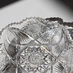Close-up of a crystal bowl with intricate cut patterns on a reflective surface.