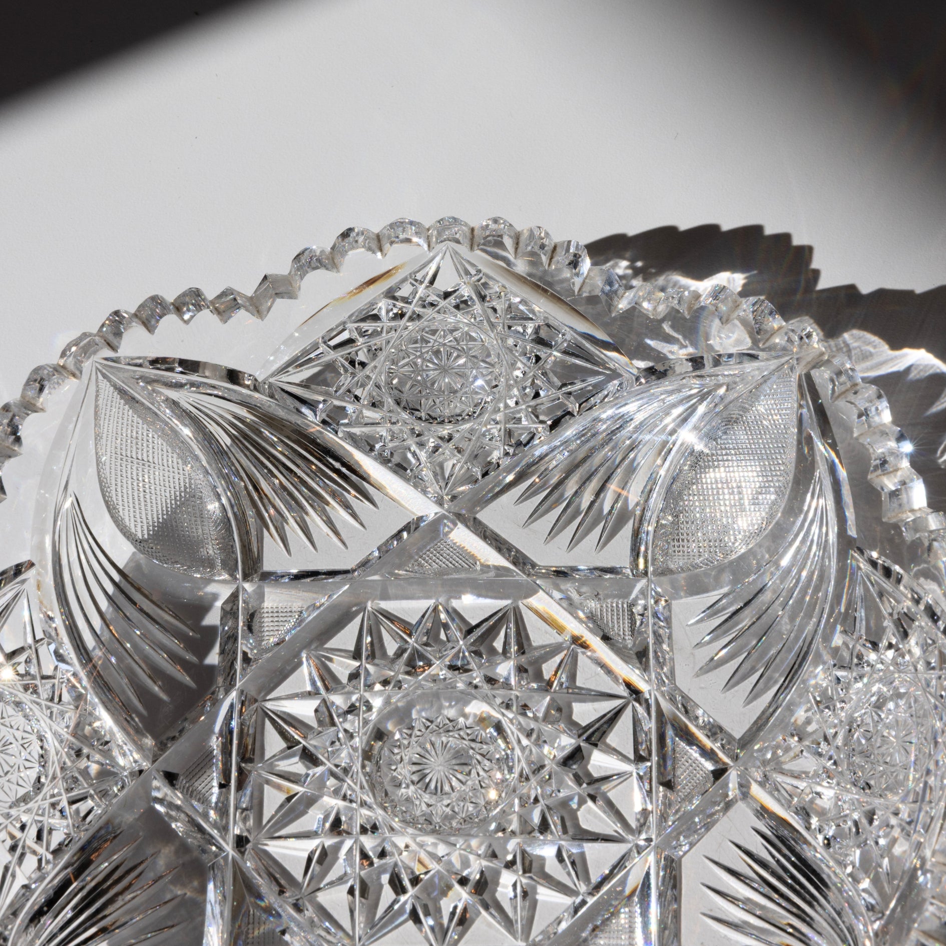 Close-up of a crystal bowl with intricate cut patterns on a reflective surface.