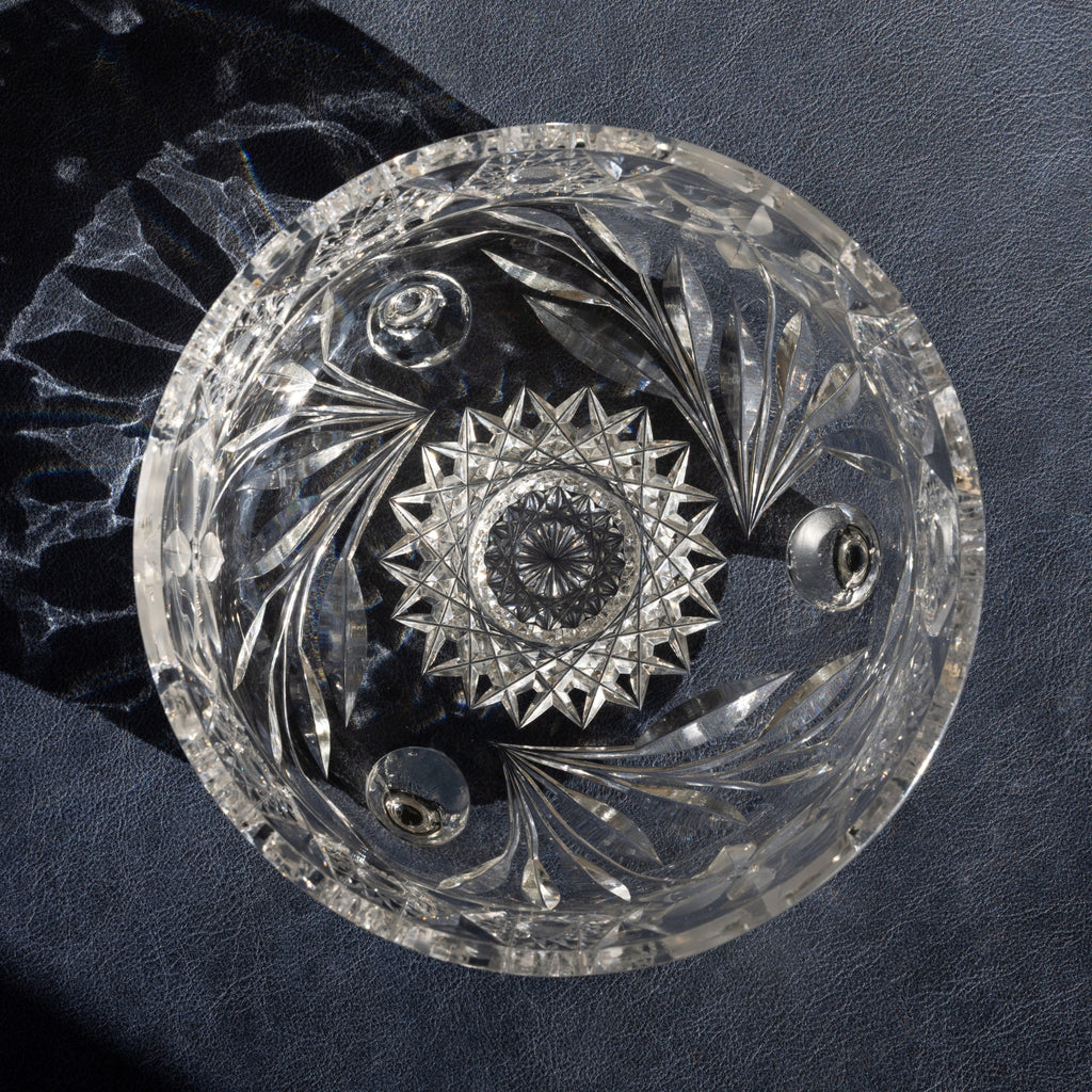 Decorative crystal dish with intricate cut patterns on a dark background