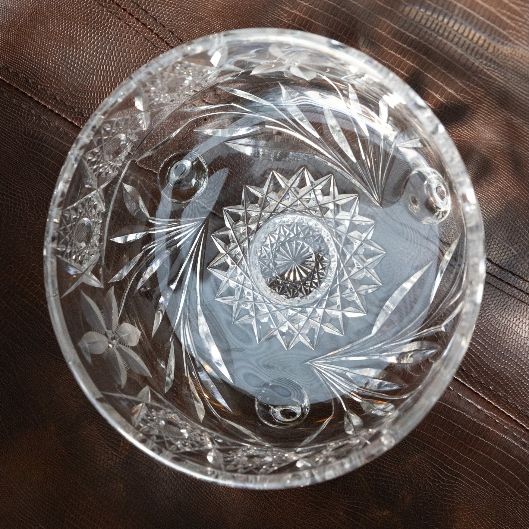 Decorative clear glass bowl with intricate cut patterns on a brown surface