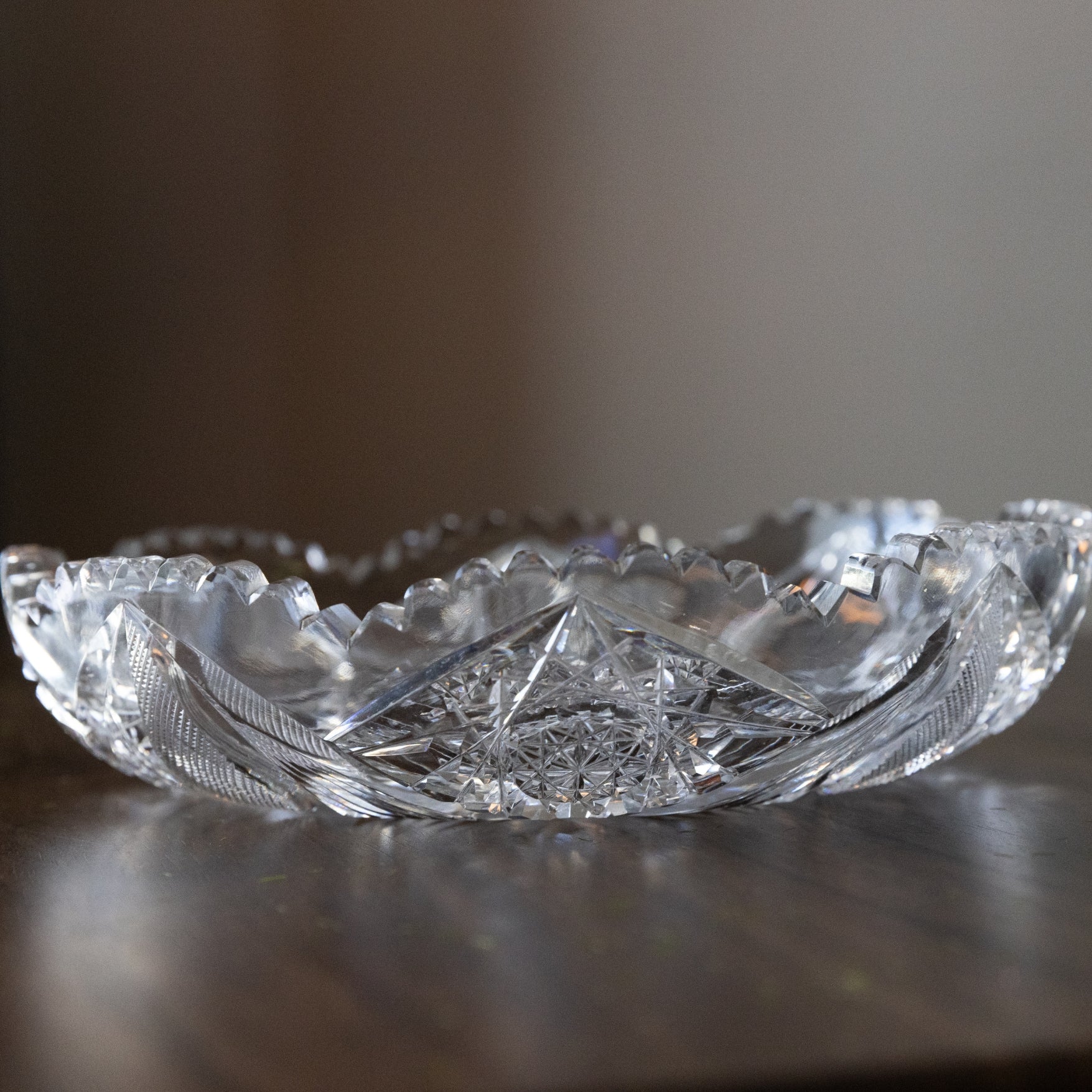 Clear crystal bowl with intricate designs on a reflective surface