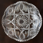Decorative crystal plate with intricate cut patterns on a dark background