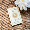 Book titled 'The Little Book of Light' on a woven surface with a white flower.